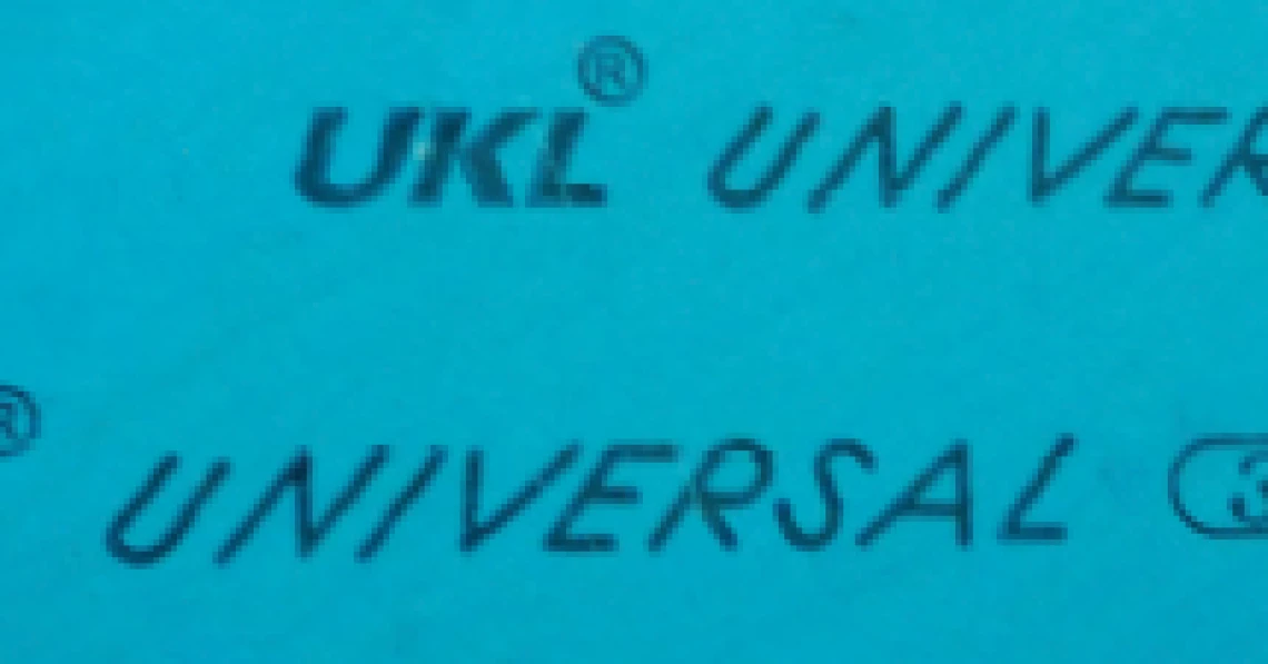 พื้นผิวสีฟ้าอ่อน มีตัวอักษรสีดำพิมพ์ซ้ำๆ กัน ประกอบด้วยคำว่า 'UKL' พร้อมสัญลักษณ์วงกลม R เล็กๆ ด้านบนขวา, คำว่า 'UNIVERSAL', และสัญลักษณ์ '(3xA)' ที่อยู่ในวงกลมรี